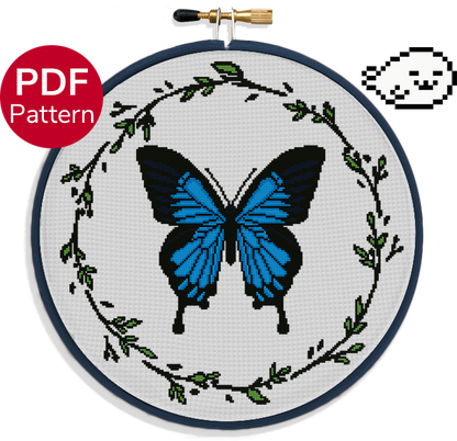 cross stitch pattern of a large ulysses butterfly with blue wings and a leaf wreath around it