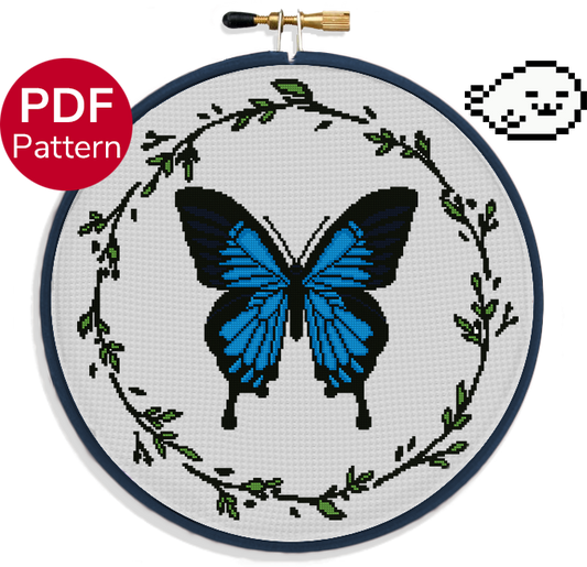 cross stitch pattern of a large ulysses butterfly with blue wings and a leaf wreath around it