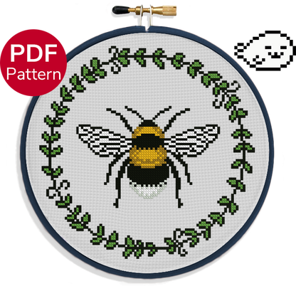 cross stitch pattern of a bumblebee surrounded by a leaf wreath