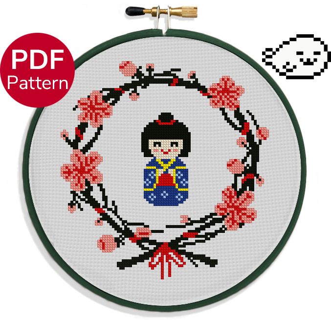 cross stitch pattern of a japanese wooden doll wearing a blue kimono surrounded by a wreath of sakura leaves