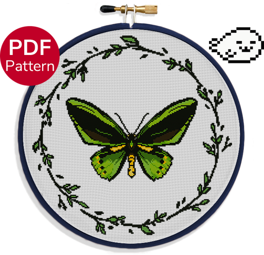 cross stitch pattern of a green birdwing butterfly with a wreath of leaves around it